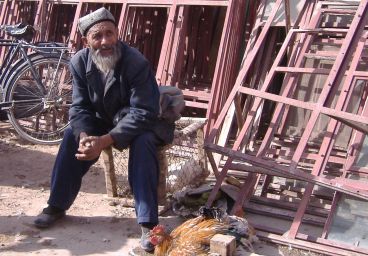 Händler mit Huhn oder Hahn beim Sonntagsmarkt in Kashgar