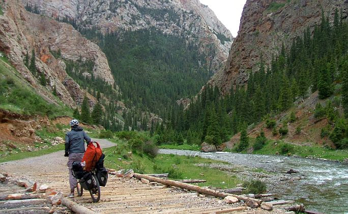 Christoph schiebt sein Rad über eine einfache Holzbrücke im Song-Köl-Tal