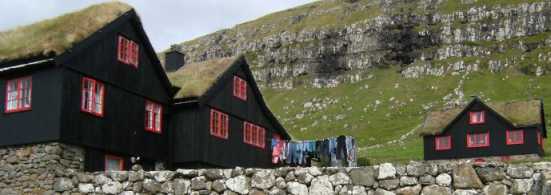 Schwarz geteerte Häuser mit Rasendächern und optimistischer  Wäscheleine in Kirkjubøur