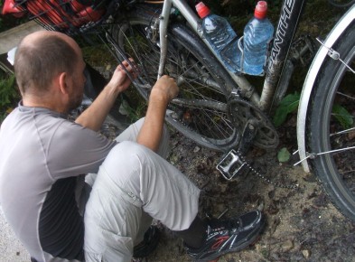 Chris neben dem Bike, um die Kette zu reparieren; Foto: Miri