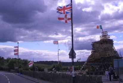 Britische Fahnen und die irische Fahne auf einer Paletten-Pyramide zur Siegesfeier der Oranier am 12. Juli, Nordirland