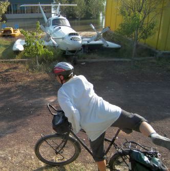 Miri schwingt sich vor einem Flügel-Boot aufs Fahrrad auf dem Campingplatz Albatros am Sewan-See, Armenien
