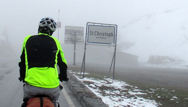 Chris on the Bike in Schnee und Nebel am Ortseingang von St. Christoph am Arlberg, Arlbergpass (1800 m)